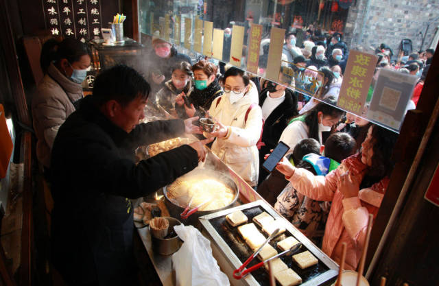 1月24日,顾客在南京老门东的小吃摊位购买特色美食。新华社发(刘建华 摄) 1月24日,顾客在南京老门东的小吃摊位购买特色美食。新华社发(刘建华 摄)