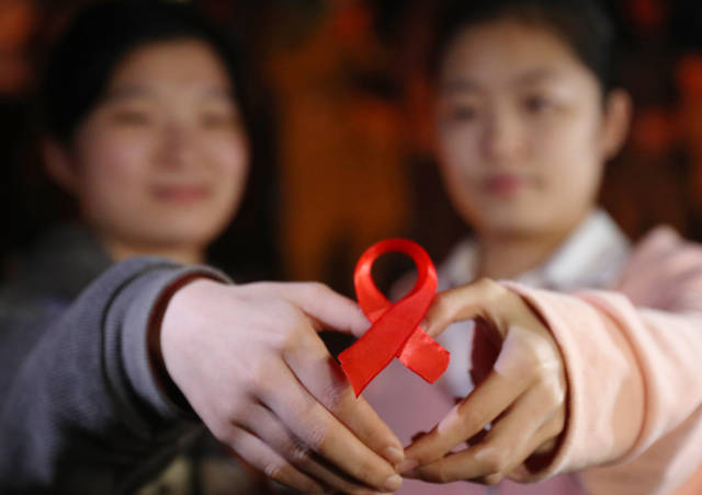 11月29日，在湖南省衡阳市南华大学广场，两名同学在活动现场展示红丝带。新华社发