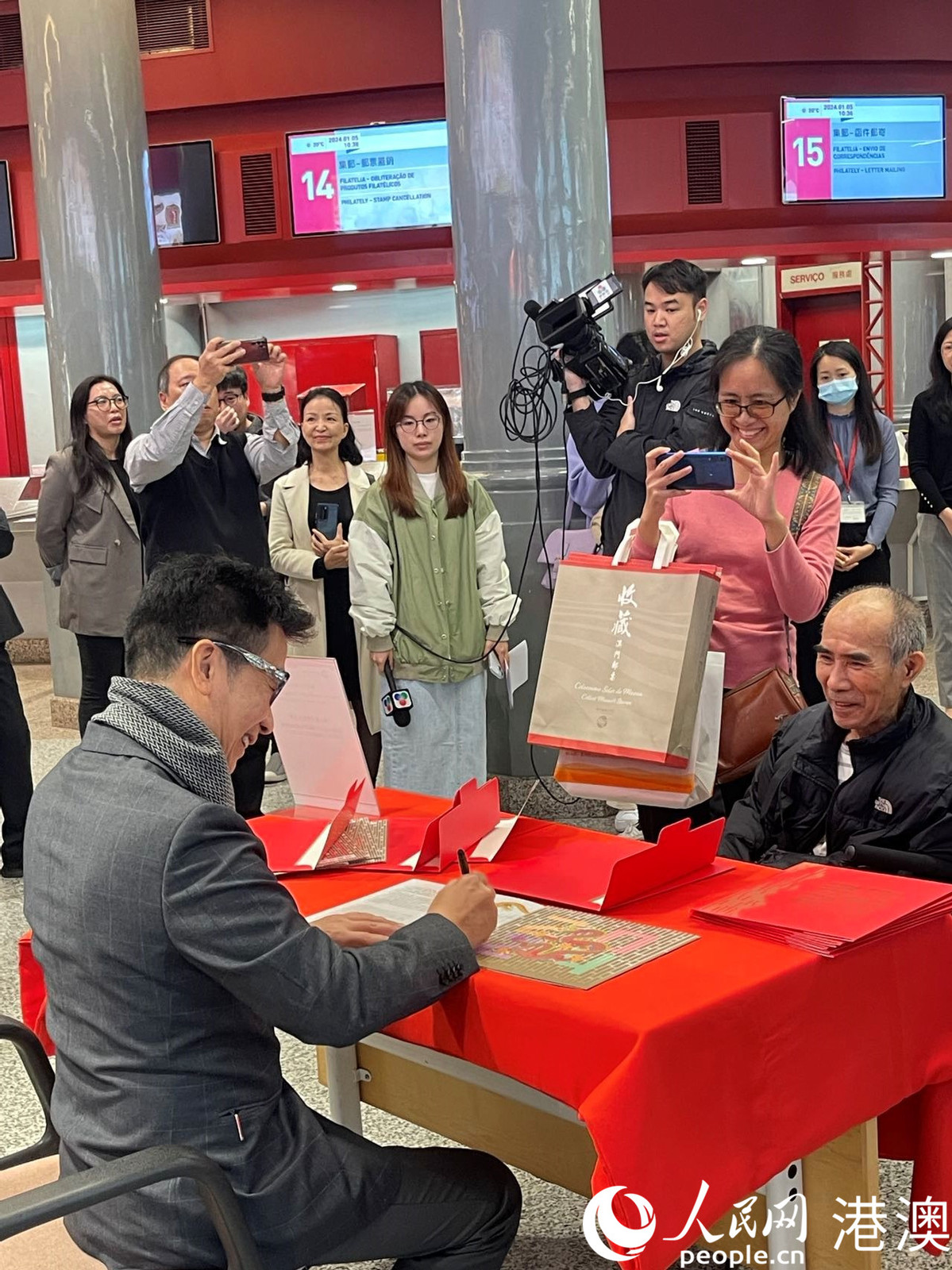 图为邮票设计师林子恩(左)为集邮爱好者签名。(本报记者富子梅摄)