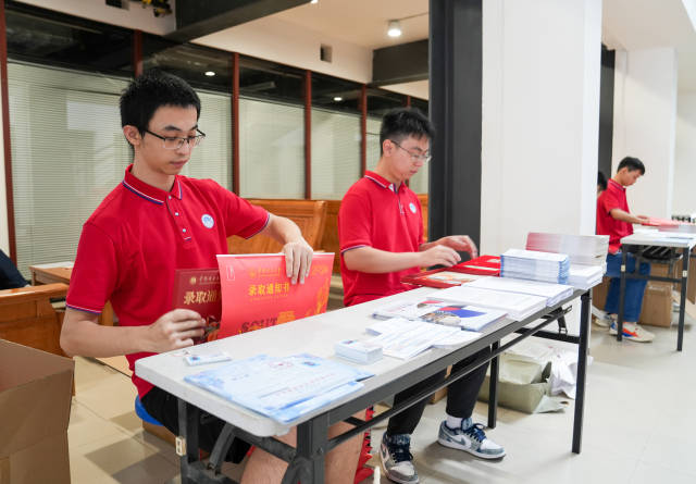 工作人员正在把录取通知书装入信封 工作人员正在把录取通知书装入信封