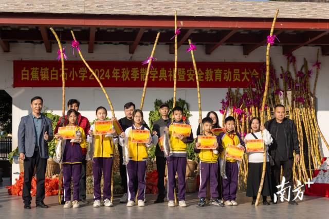 斗门区白石小学校长李杨（左一）向荣获学习标兵的学生发放奖品。 